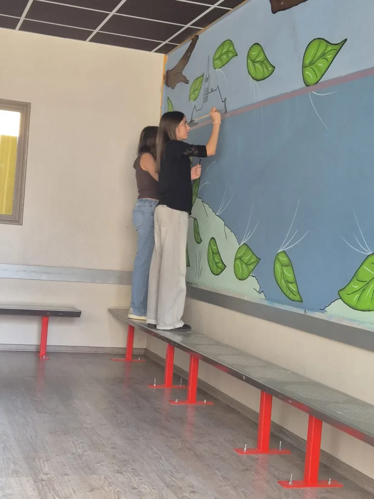 Deux élèves internes peignent la fresque du foyer
